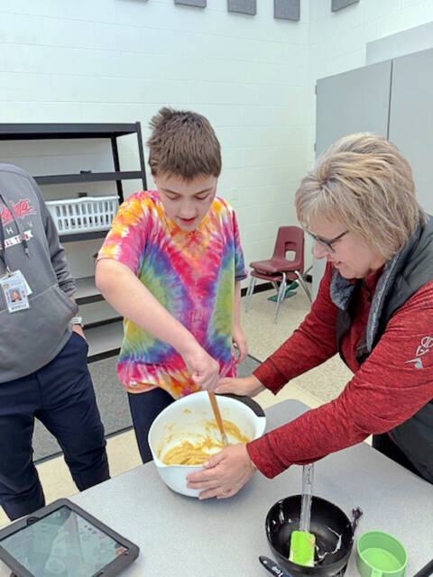 Jule Bullington helps Nicholi Stahl stir a batter in the life skills lab at MMS.